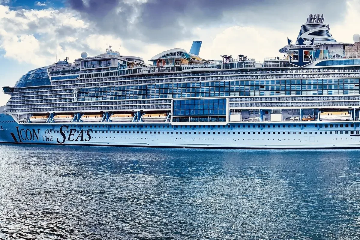 A large cruise ship, named Icon of the Seas, floating on a blue ocean.